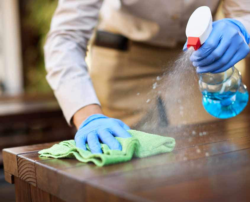 Close Up Of Waitress Disinfecting Tables At Outdoor Cafe